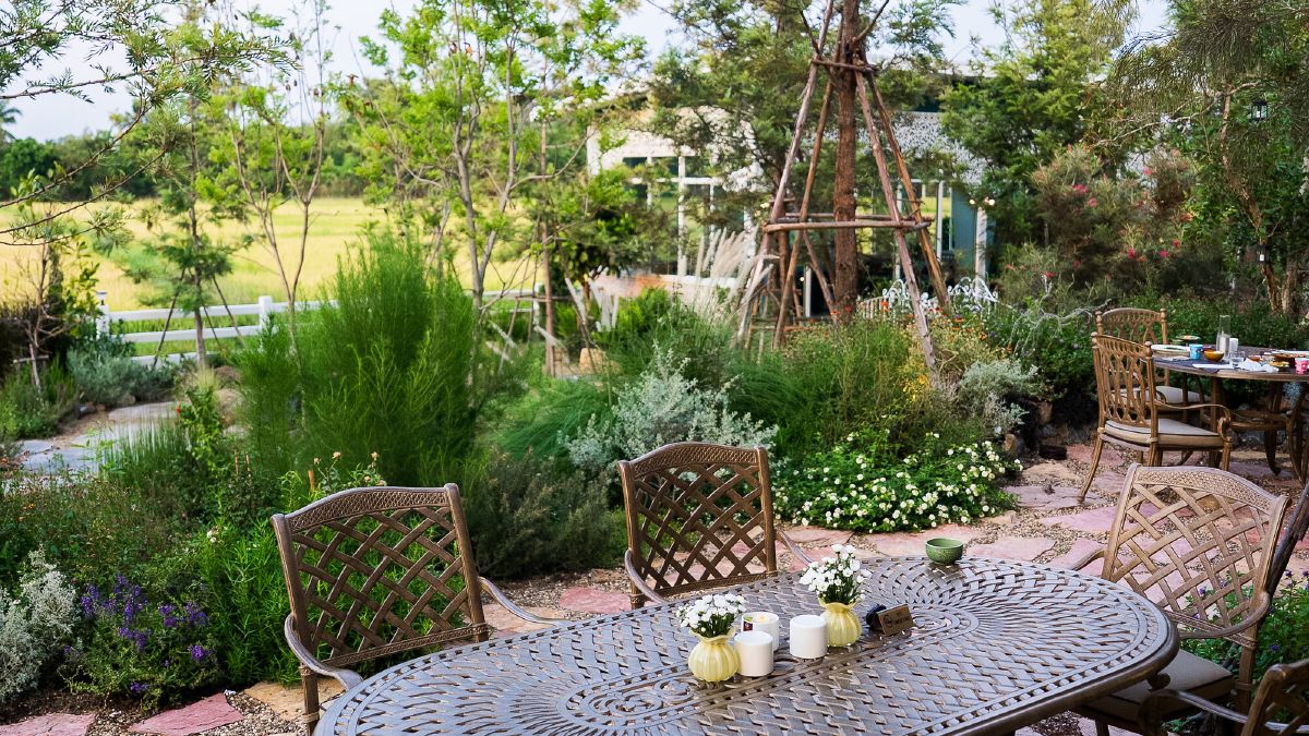 A laid table on the garden terrace at WIROON, with planting and paddy fields beyond
